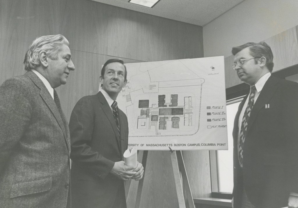 Chancellor Carlo L. Golino (left) and two unidentified men in front of a plan for Columbia Point campus detailing its different phases of construction.