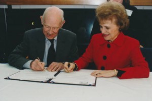 Judge W. Arthur Garrity signing the deed of gift for his chamber papers with UMass Boston Chancellor Sherry Penney. As a result over 60 boxes of files from the 1972 desegregation court case, Morgan v. the Boston School Committee, were donated to the Joseph P. Healey Library. Archivist Elizabeth Mock in background.