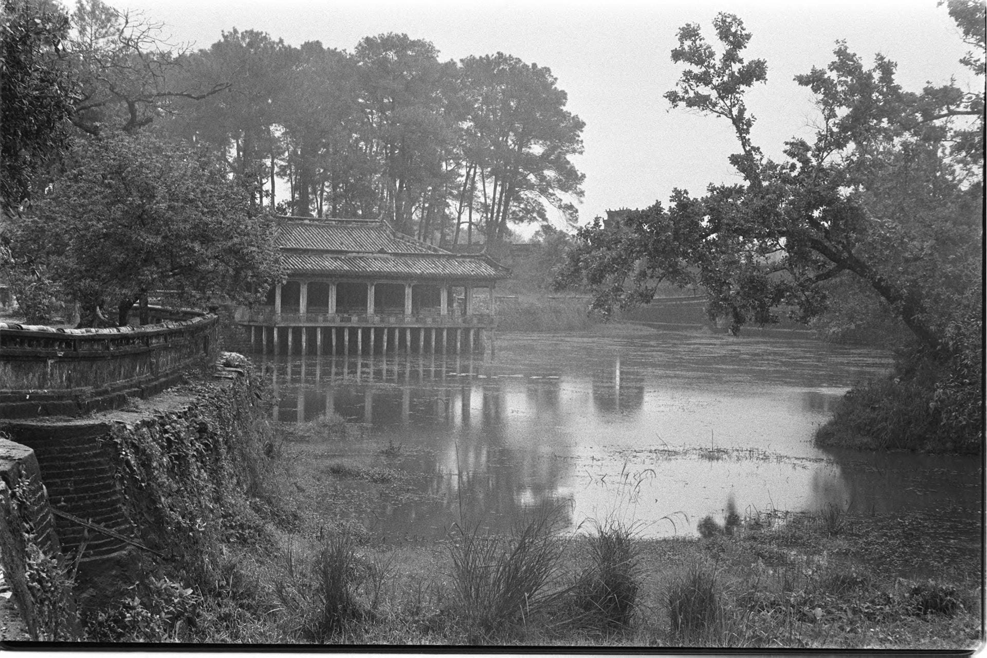 Black-and-white photo of an Imperial tomb on water surrounded by trees