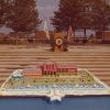 Color photograph of a cake replica of the university campus in the foreground with steps and a podium in the background