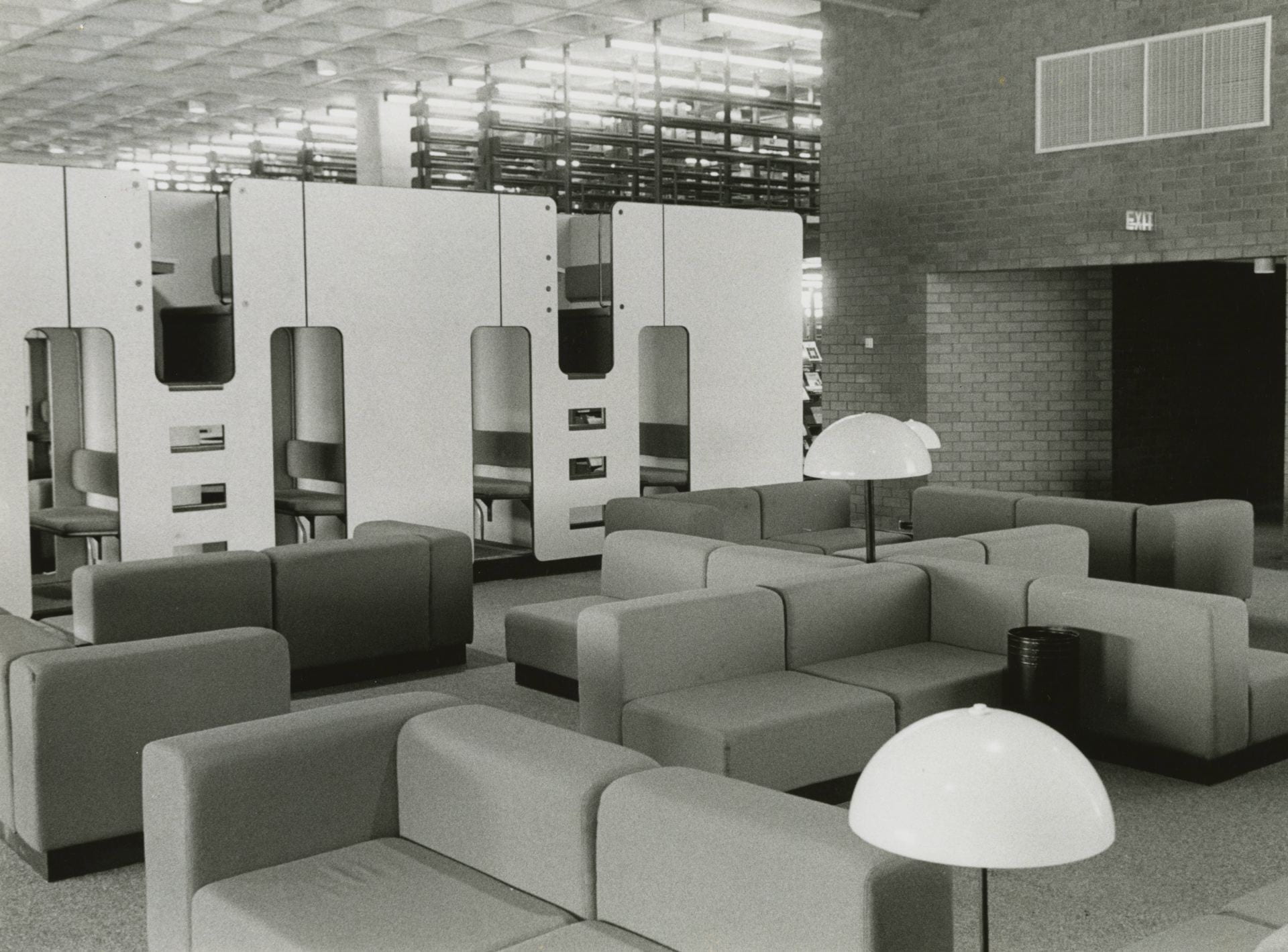 Black-and-white photo of couches, study cubicles, and lamps inside the Healey Library