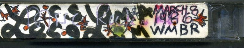 Image of the side of a cassette tape with writing in marker
