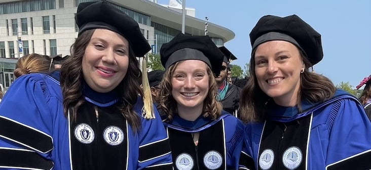 Three new PhDs in gowns and hoods