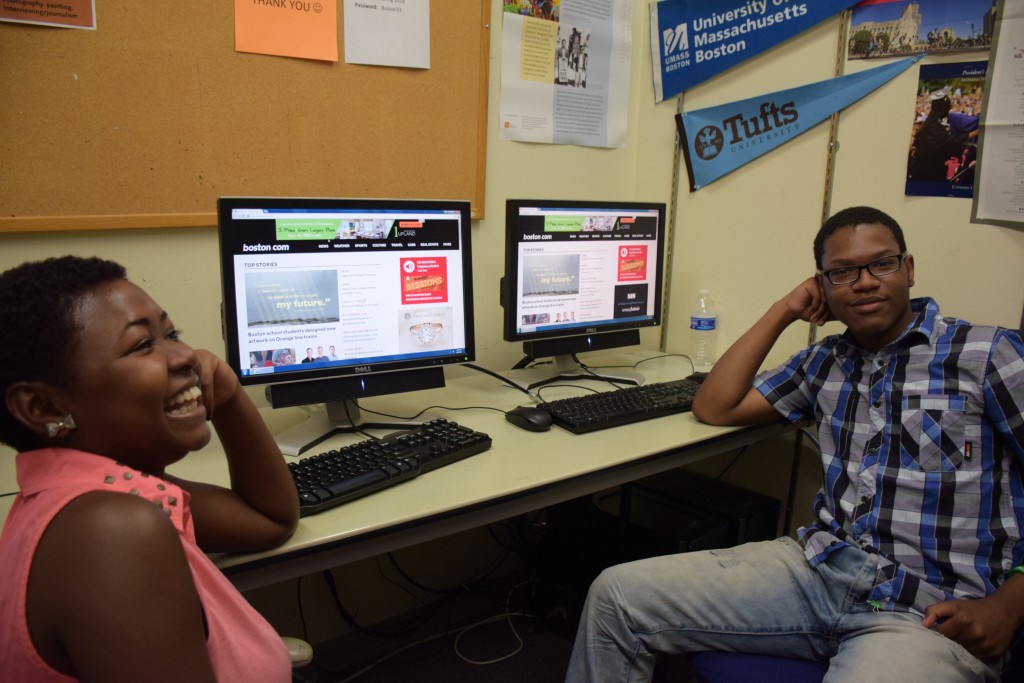 Ann and Quanye sit in front of computers showing Boston.com story. In Transit was the featured story Monday morning, August 8, 2016