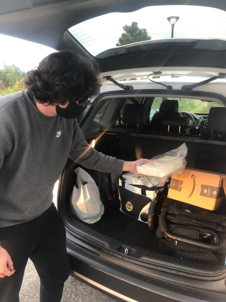Image of Healey Library student worker placing curbside pickup items into the trunk of a patron's car