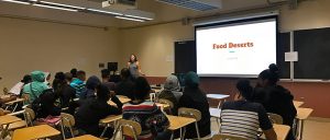 "Food desert" displays on screen as students sit in the back and watch their instructor define and explain what words mean.