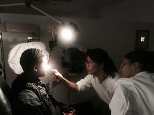 Optometry holds flashlight close to eye. 