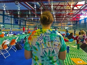 Back of councilor's colorful tie-dye t-shirt standing in front of the gym.