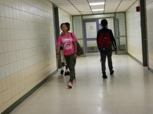 two boy students, and a TA walking down the hallway.