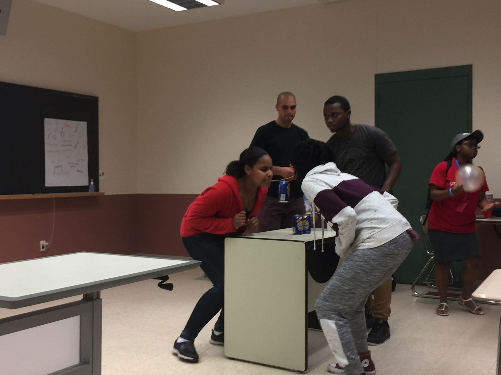students try to build a tower from Pepsi bottles, balancing them on a single spaghetti