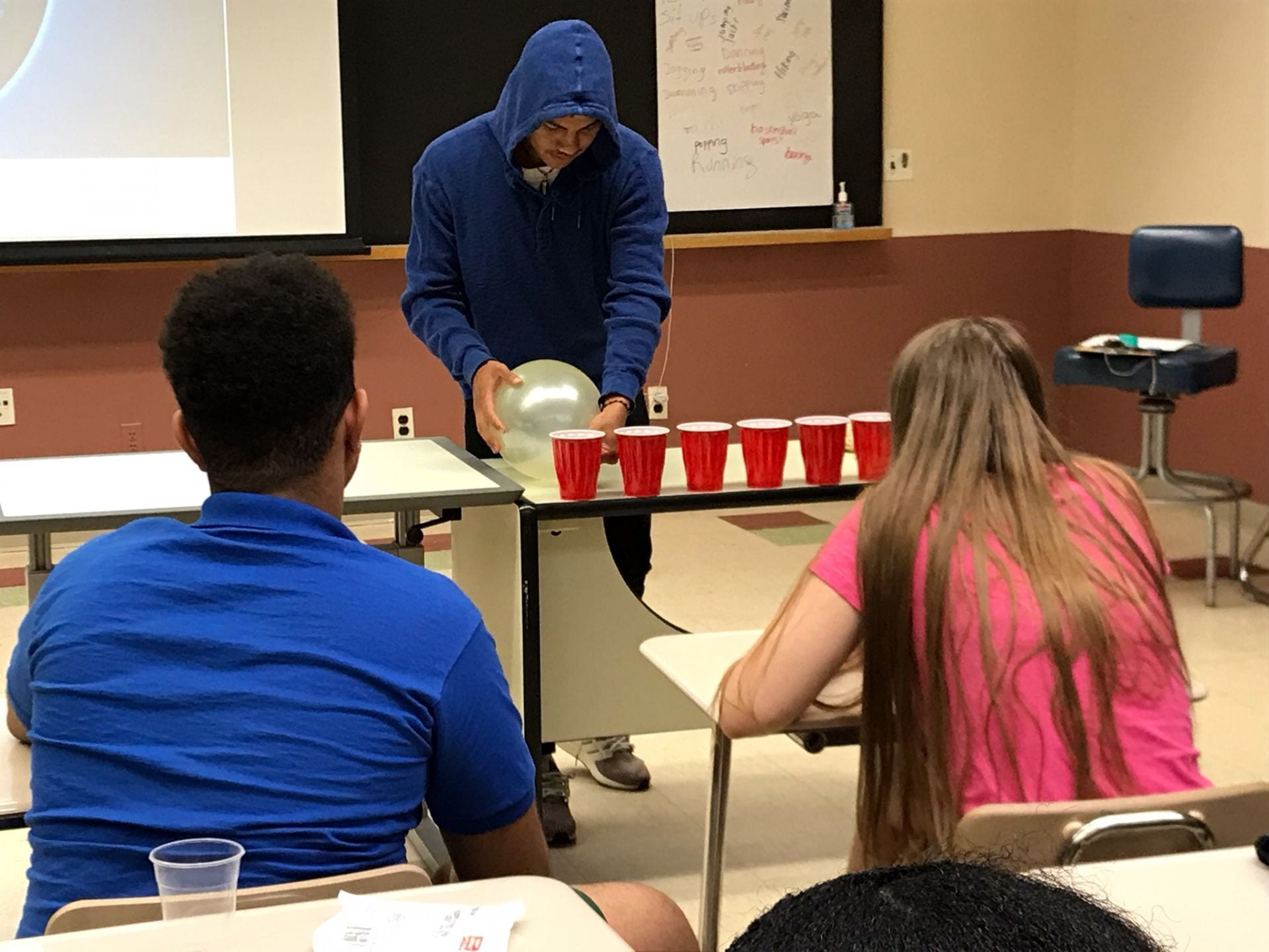 a student tries to blow away plastic cups