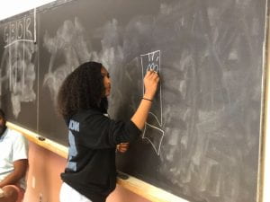 Student drawing on chalk board.