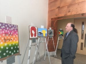 The urban scholars director walks around and looks at a painting from the students in the art class